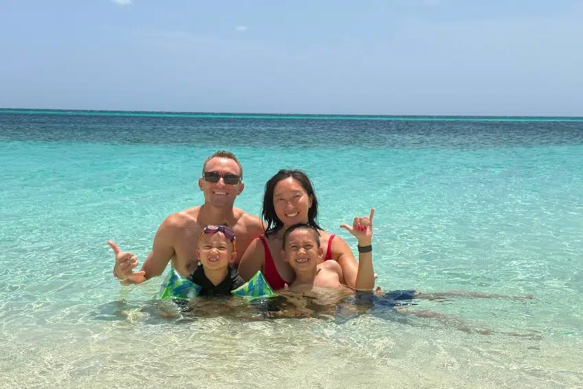 Family smiling in shallow turquoise water at Bahia de las Aguilas