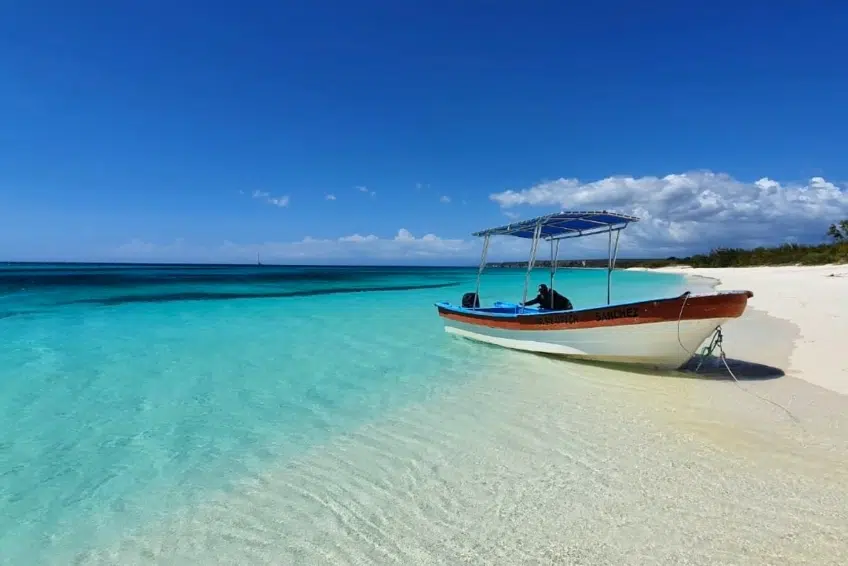 Tour boat with canopy anchored on white sand at Bahia de las Aguilas