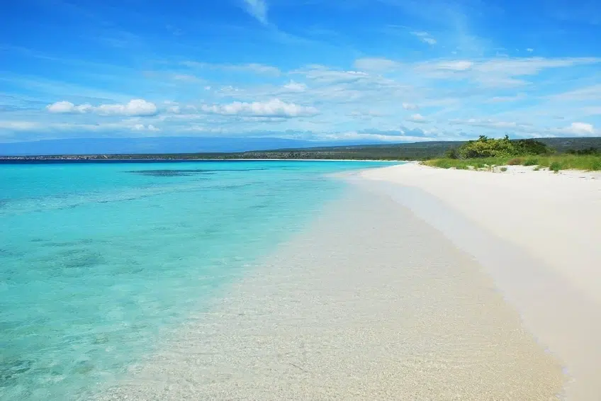 Pristine empty white sand shoreline stretching along clear turquoise water of Bahia de las Aguilas