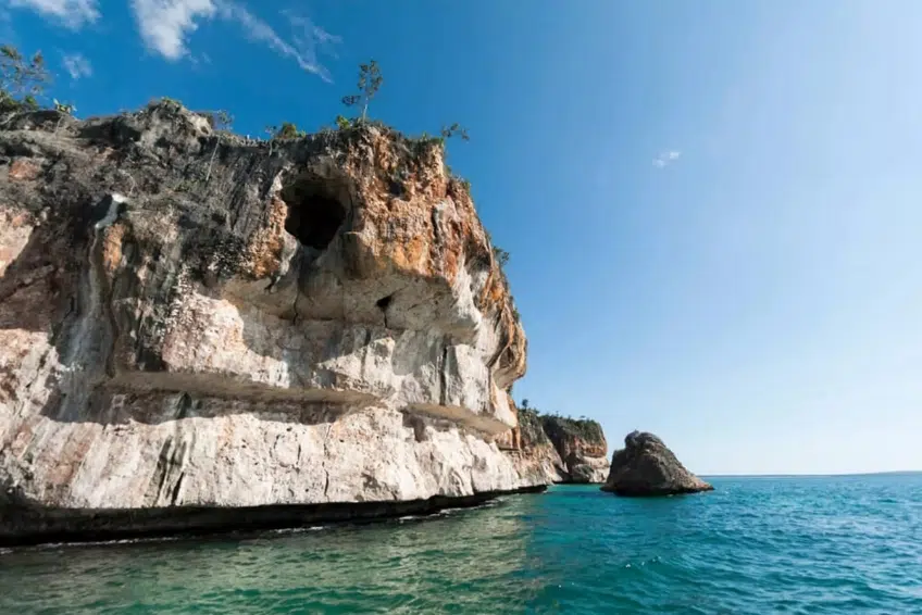 Towering limestone cliff above turquoise sea in Jaragua National Park
