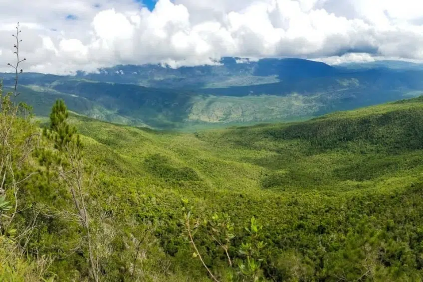 Panoramic view of rolling green hills and cloud-covered mountains of Sierra de Bahoruco