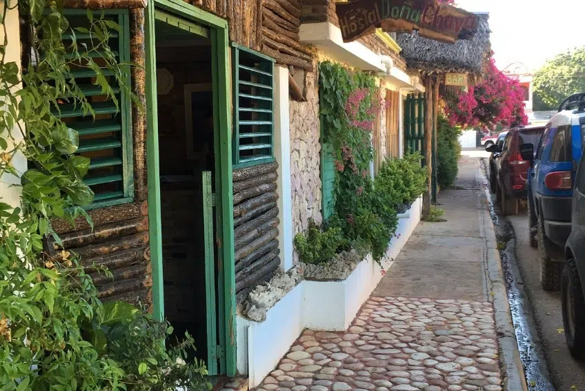 Pedernales street with flower-covered hostal and cobblestone sidewalk