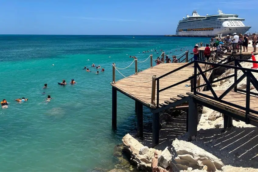 Snorkelers near wooden dock with cruise ship docked at Cabo Rojo Cruise Port