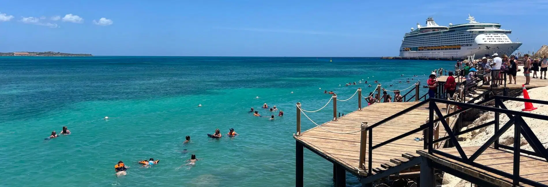 Snorkelers near wooden dock with cruise ship docked at Cabo Rojo Cruise Port