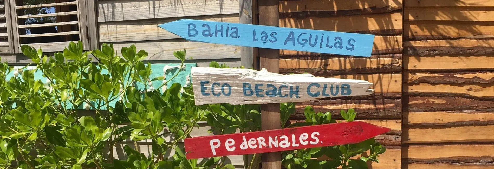 Wooden directional signs pointing to local destinations in Cabo Rojo, Dominican Republic