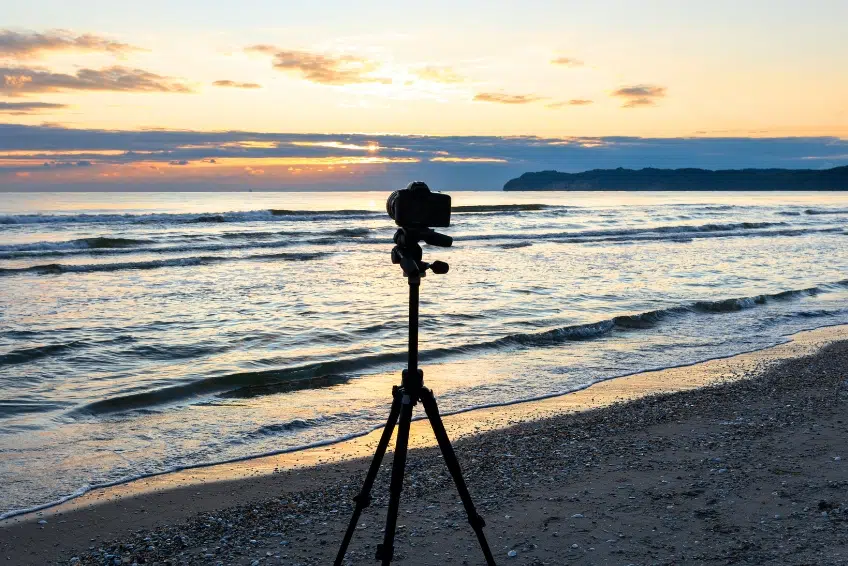 Camera on tripod silhouetted against Bahia de las Aguilas for sunrise