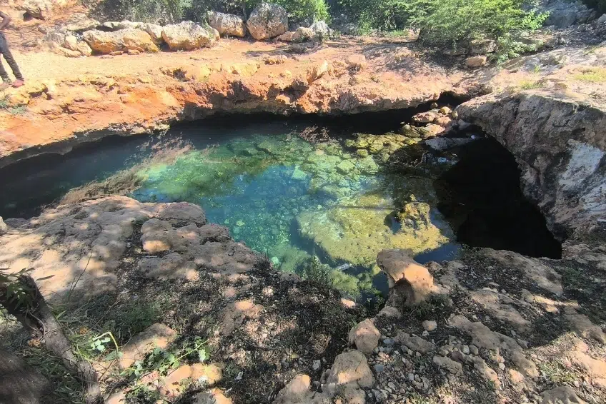Turquoise green water filling a rocky natural pool of Pozos de Romeo