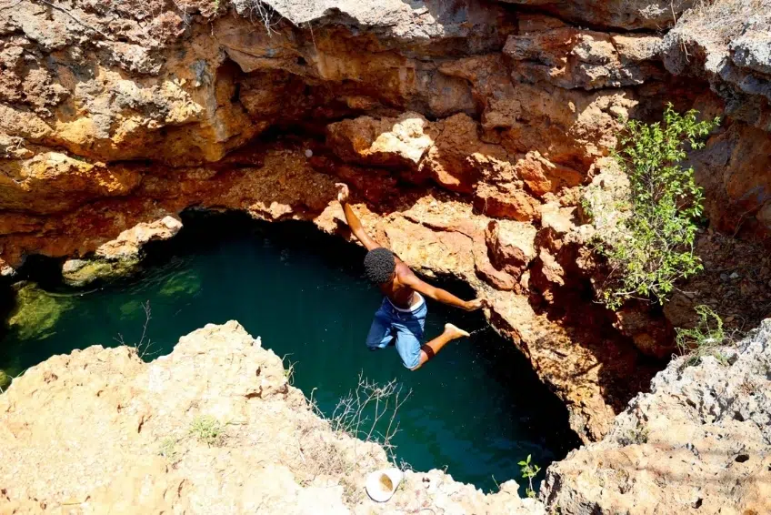 Person jumping into deep natural rock pool at Pozos de Romeo