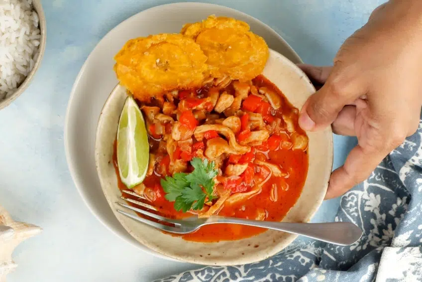 Dominican stewed lambi (conch) with tostones, lime and cilantro garnish