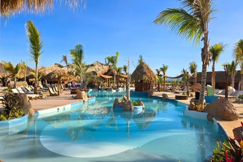 Pool with palm trees and thatched-roof palapas