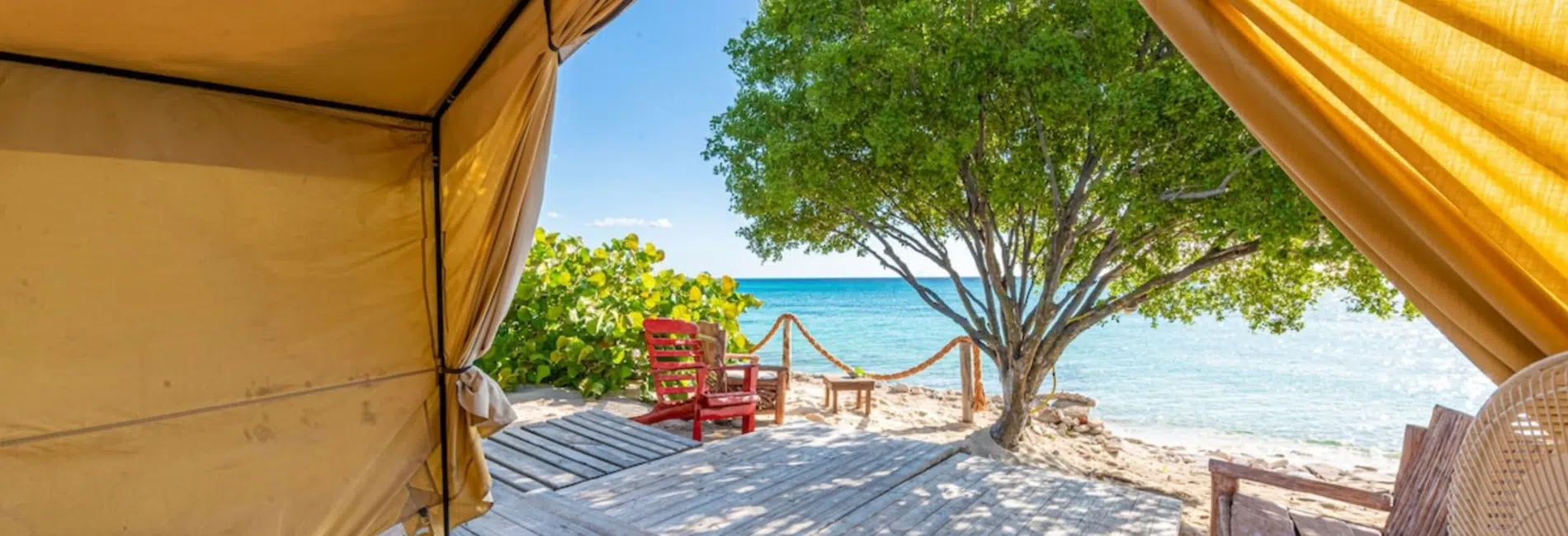 View from inside glamping tent overlooking beachfront deck and ocean