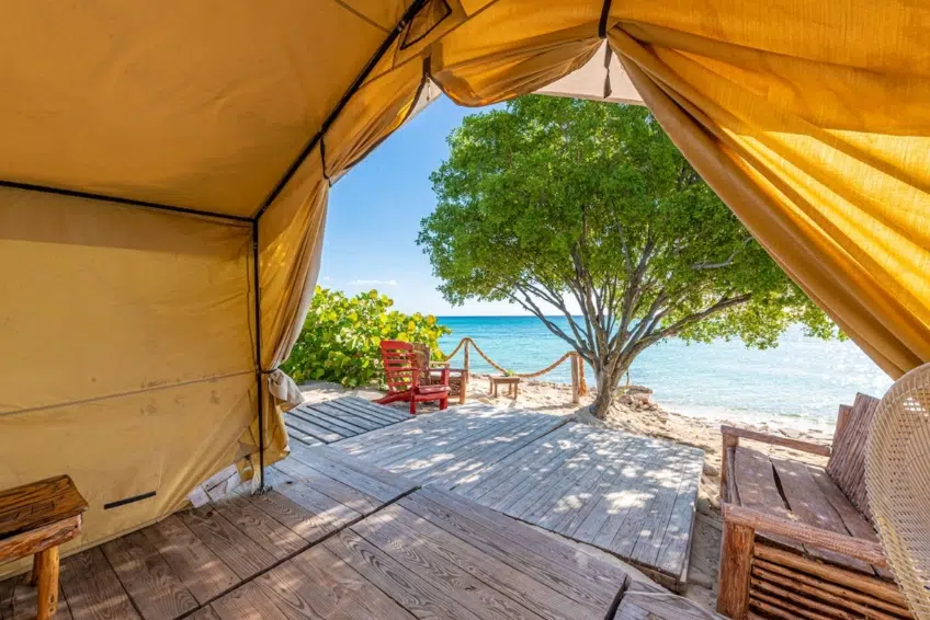 Glamping tent doorway framing turquoise sea and wooden deck view