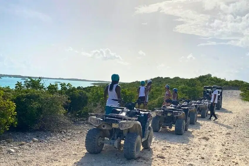 ATV tour group stopped on coastal trail overlooking turquoise water of Cabo Rojo, DR