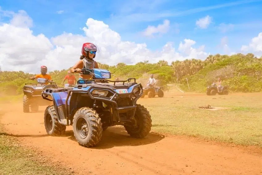 Group of ATV riders racing across open dusty field in Cabo Rojo