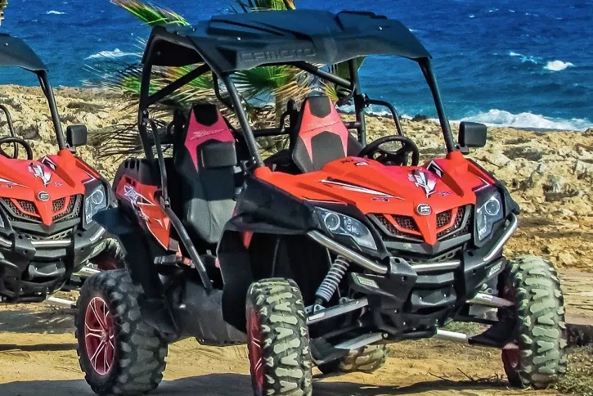 Red off-road buggy parked on rocky coastal cliff overlooking ocean in Cabo Rojo, DR