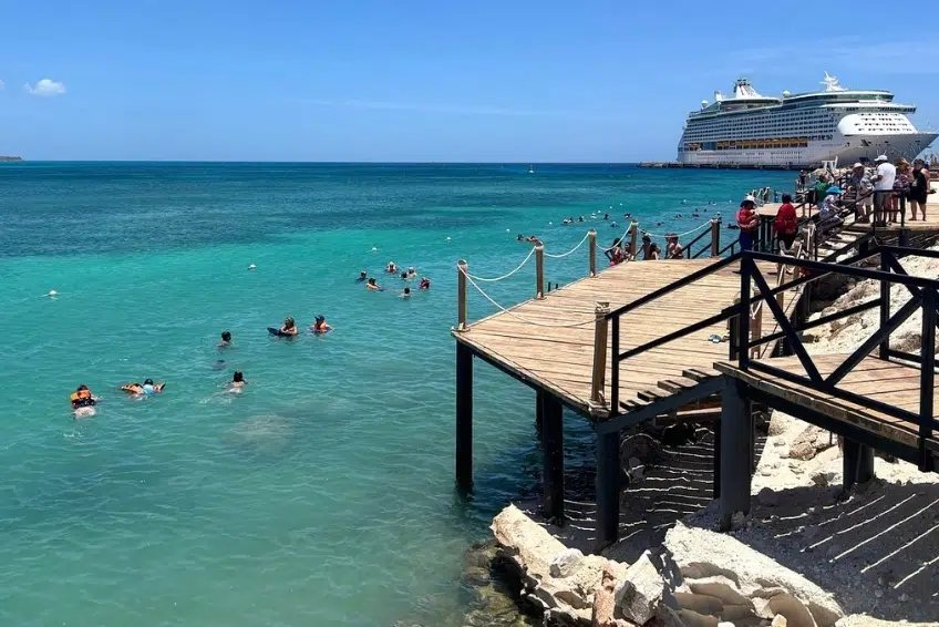 Swimmers off wooden dock beside docked cruise ship at Cabo Rojo Cruise Port