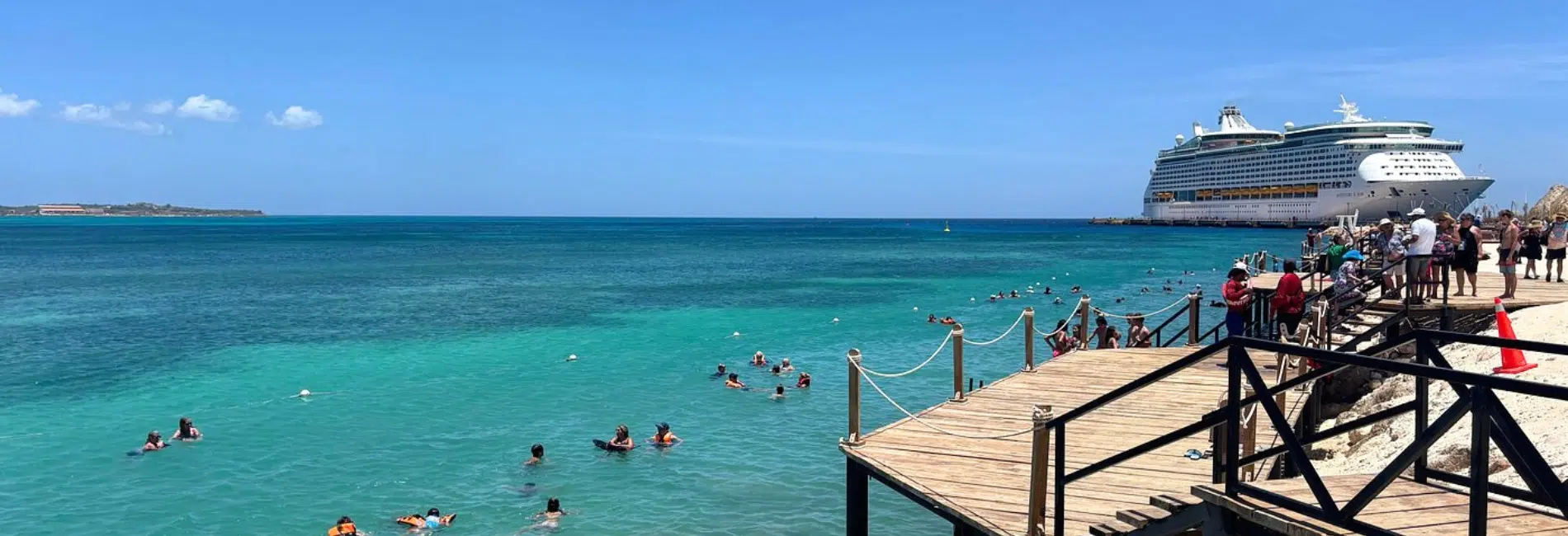 Swimmers off wooden dock beside docked cruise ship at Cabo Rojo Cruise Port
