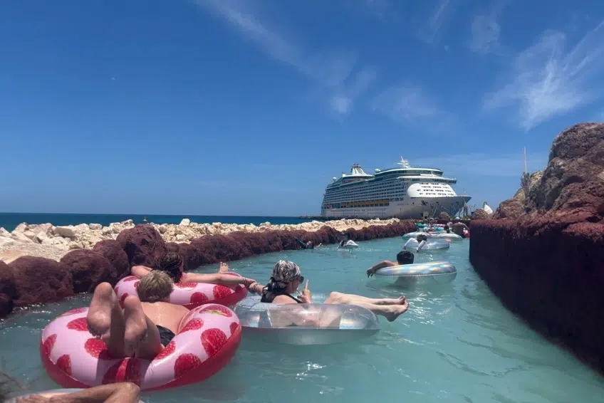 Guests floating on inner tubes in lazy river with cruise ship docked behind at the Cabo Rojo Cruise Port