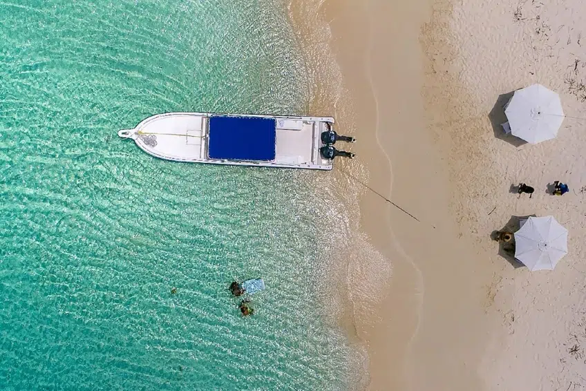Boat beached on white sand with white umbrellas at Eco del Mar Beach Club