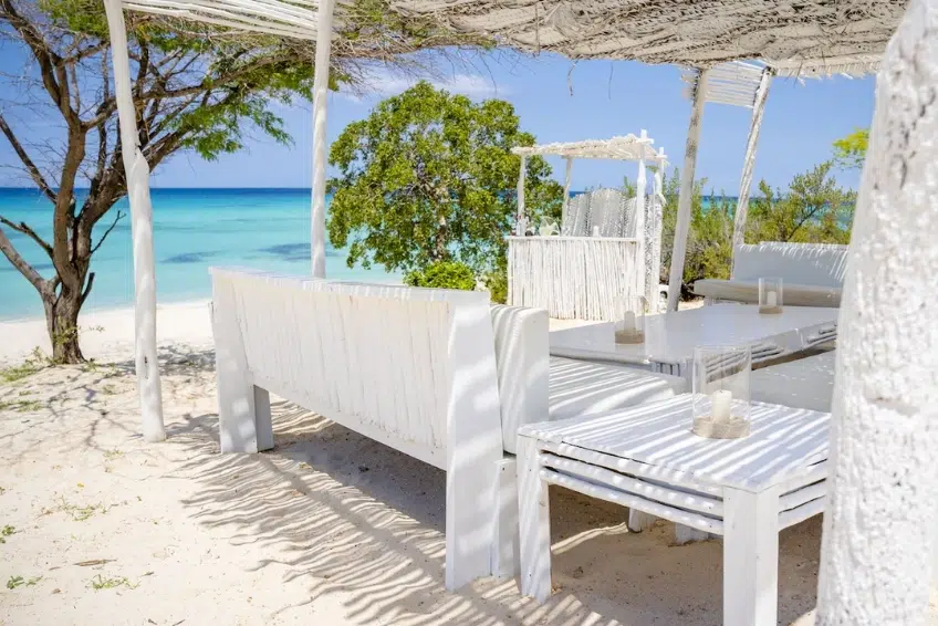 Beachfront lounge seating under thatched canopy with ocean views at Eco del Mar Beach Club