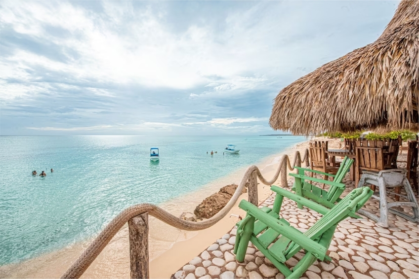Green Adirondack chairs overlooking turquoise beach at Glamping EcoLodge Cueva de las Aguilas