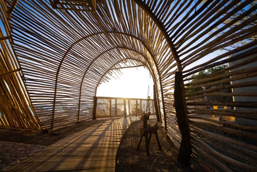 Arched bamboo tunnel pathway with sunlight shining through at EcoLodge Cueva de las Aguilas
