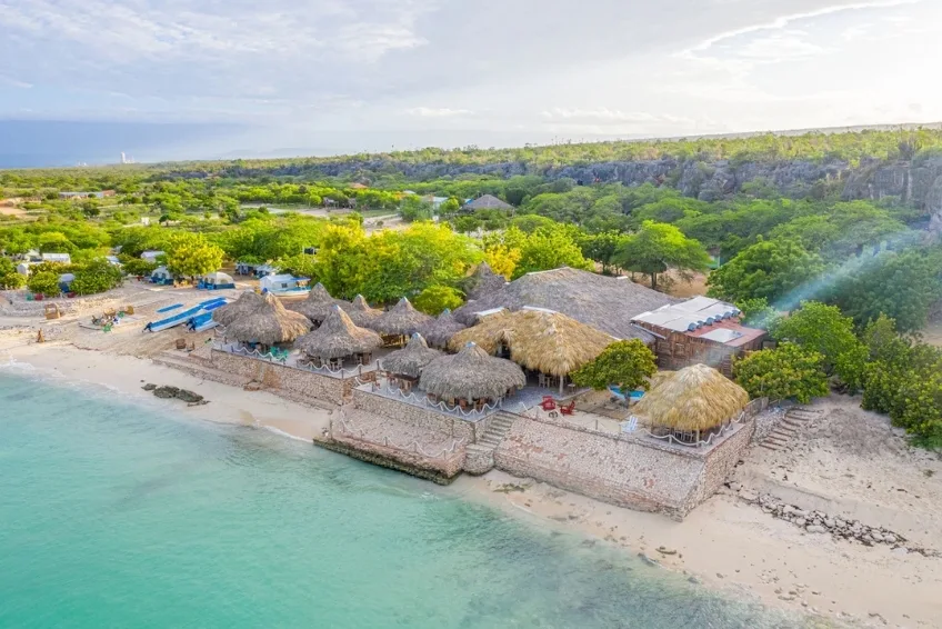View of beachfront Glamping EcoLodge Cueva de las Aguilas with thatched roof huts