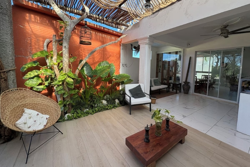 Boho patio with tropical plants and wicker accent chair at Hotel Casa Bajari