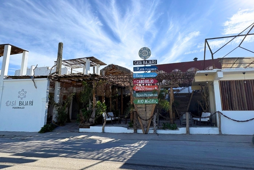 Casa Bajari exterior with colorful directional signs and thatched roof