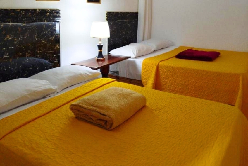 Double room at Hotel El Almendro with bright yellow bedspreads and marble headboard