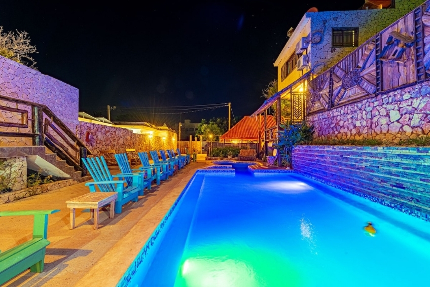 Illuminated hotel pool glowing blue at night with lounge chairs at Hotel Vista de Aguilas Ecolodge