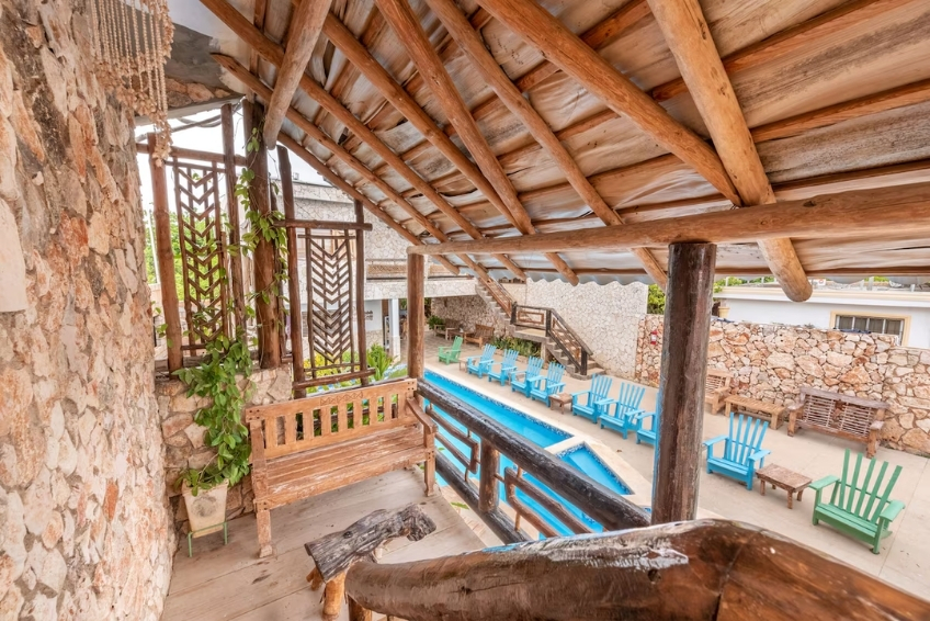 Rustic wooden balcony overlooking hotel pool with blue lounge chairs at Hotel Vista de Aguilas Ecolodge