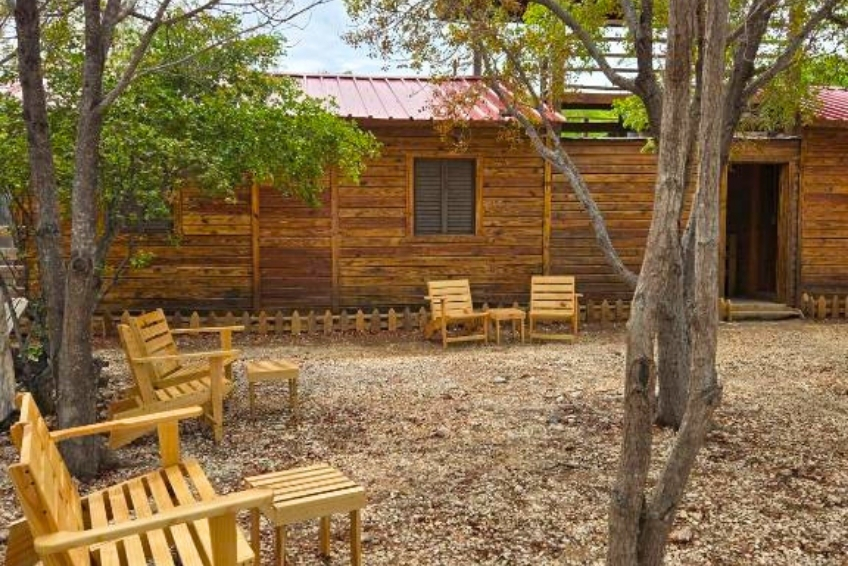 Wooden cabin exterior with gravel courtyard and Adirondack chairs at La Casita de La Cueva