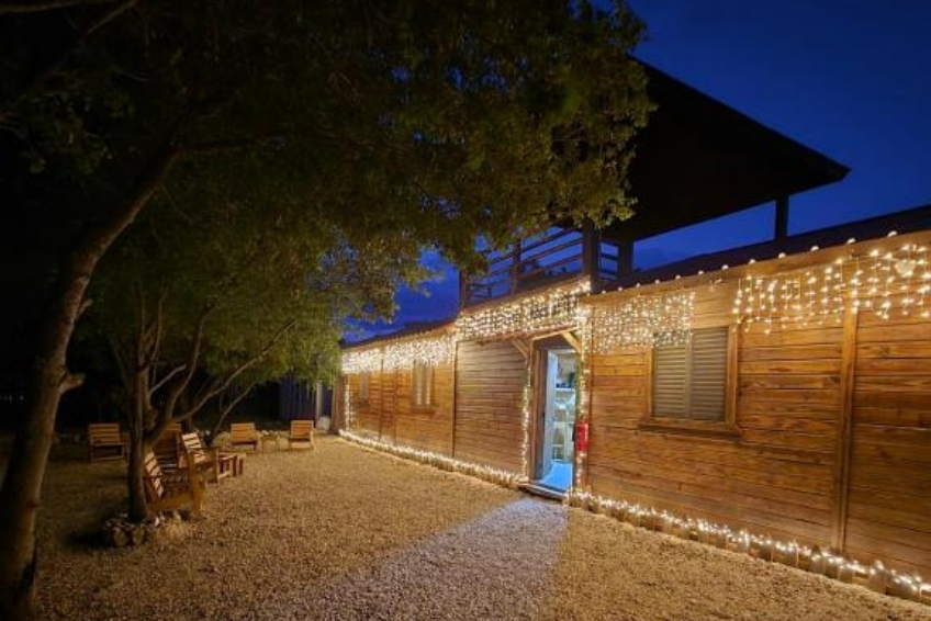 Rustic wooden cabin with red roof and outdoor wooden chairs at La Casita de La Cueva