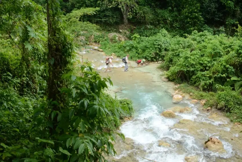 Hikers crossing shallow rocky river