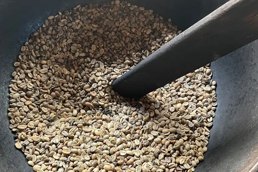 Green coffee beans being stirred in a roasting pan at Polo Coffee Tour