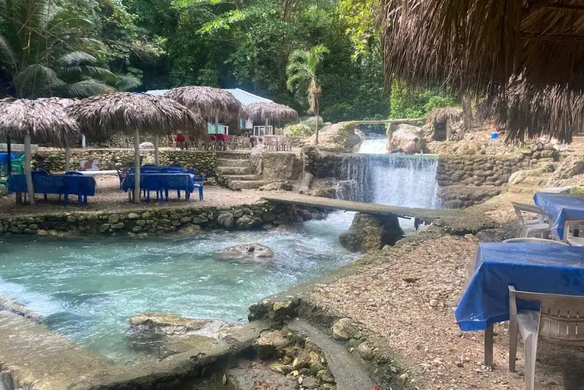 Outdoor restaurant with thatched umbrellas beside rushing waterfall pool