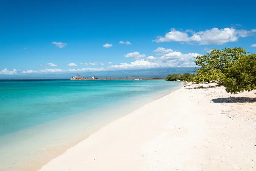 Calm white sand beach with turquoise water and distant ship at Baby Beach