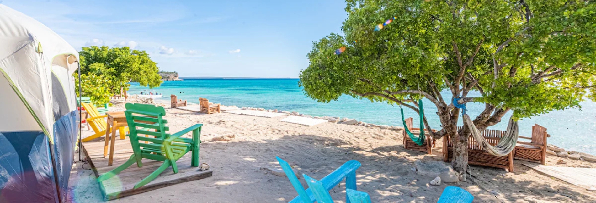 Colorful beach chairs and hammock beside turquoise ocean water at Glamping EcoLodge Cueva de las Aguilas