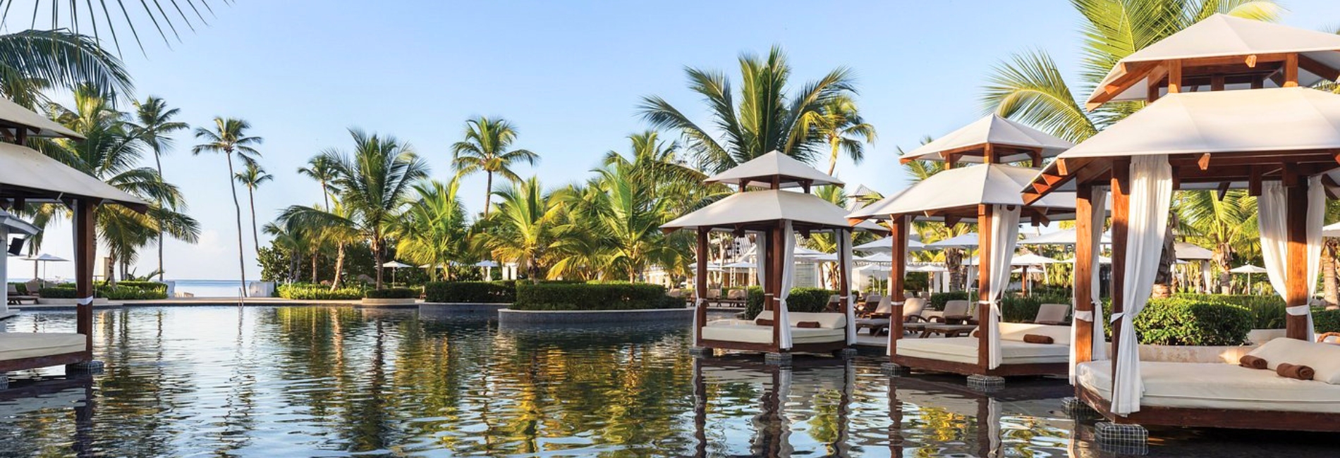 Luxury poolside cabanas with white curtains and palm trees with beach views