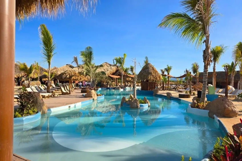 Lagoon-style resort pool with palm trees and thatched huts in Cabo Rojo, Dominican Republic