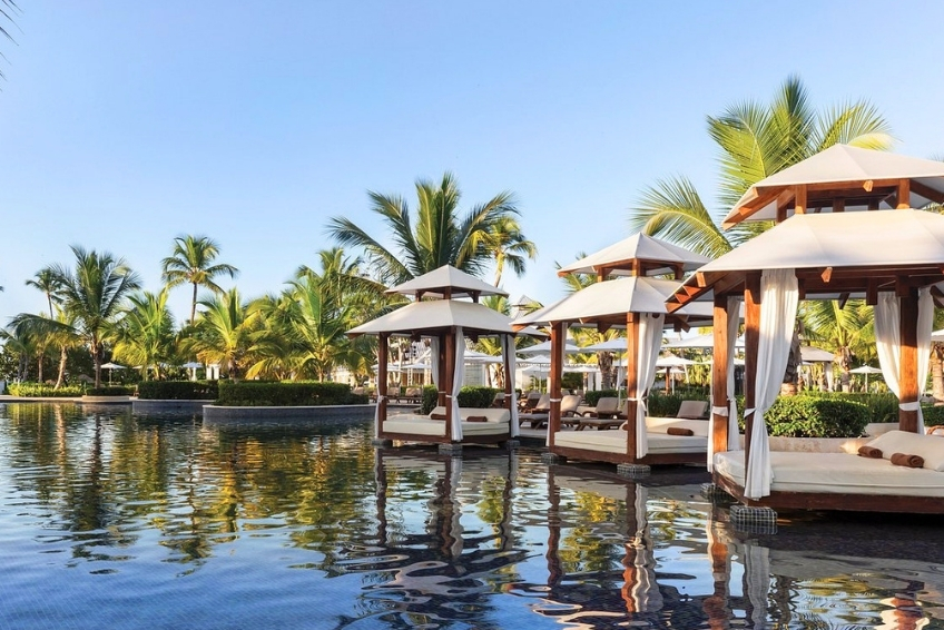 Luxury poolside cabanas with white curtains and palm trees
