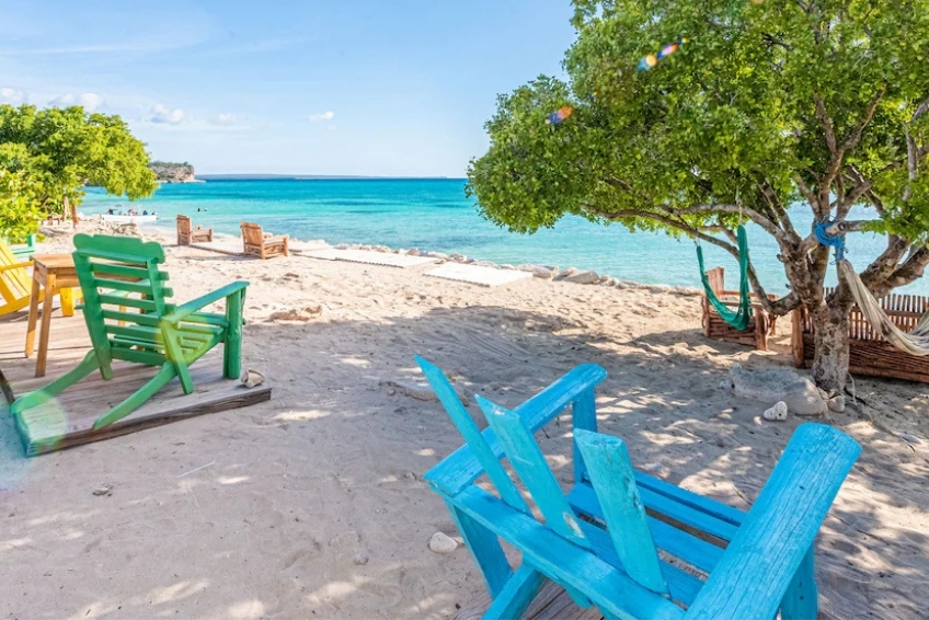 Colorful beach chairs and hammock beside turquoise ocean water at Glamping EcoLodge Cueva de las Aguilas