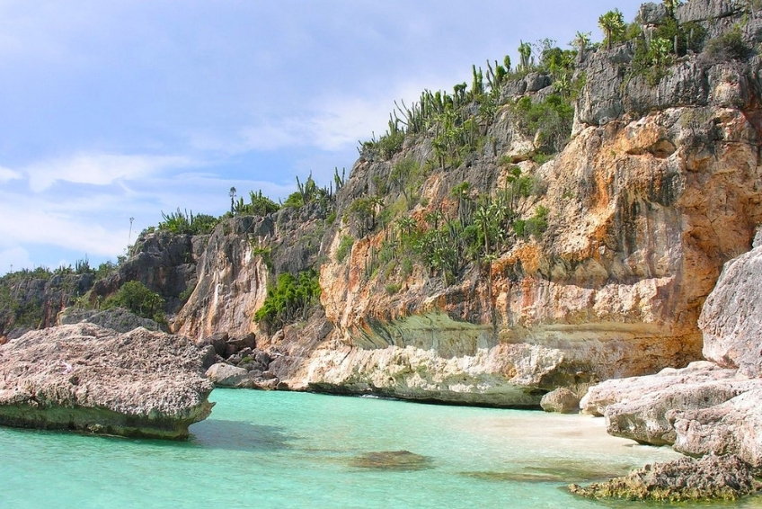 Rocky limestone cliffs with cacti overlooking clear turquoise water in Cabo Rojo
