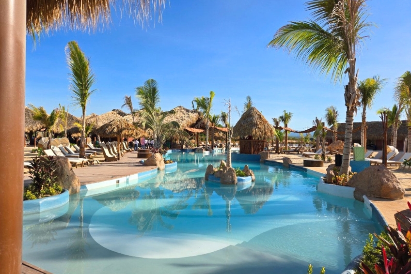 Tropical pool with palapa umbrellas and palm trees at Baby Beach Club, Cabo Rojo