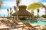 Resort pool area with thatched palapa bar and lounge chairs at Baby Beach Club