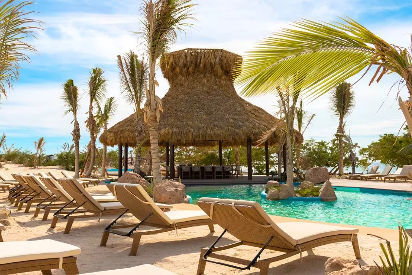 Resort pool area with thatched palapa bar and lounge chairs at Baby Beach Club