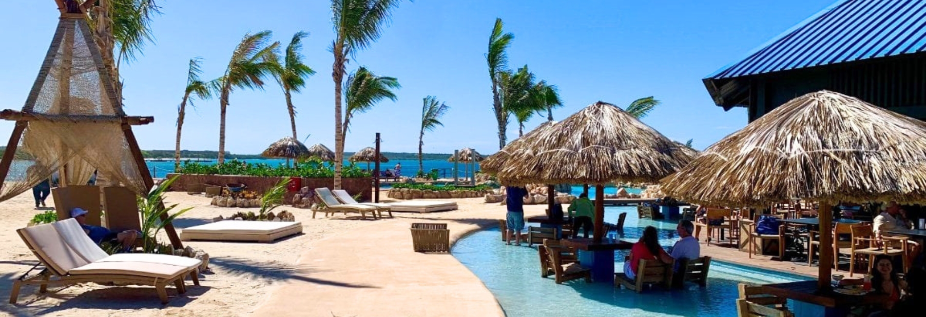 Beachside pool bar area at Baby Beach Club with palapa umbrellas and ocean view