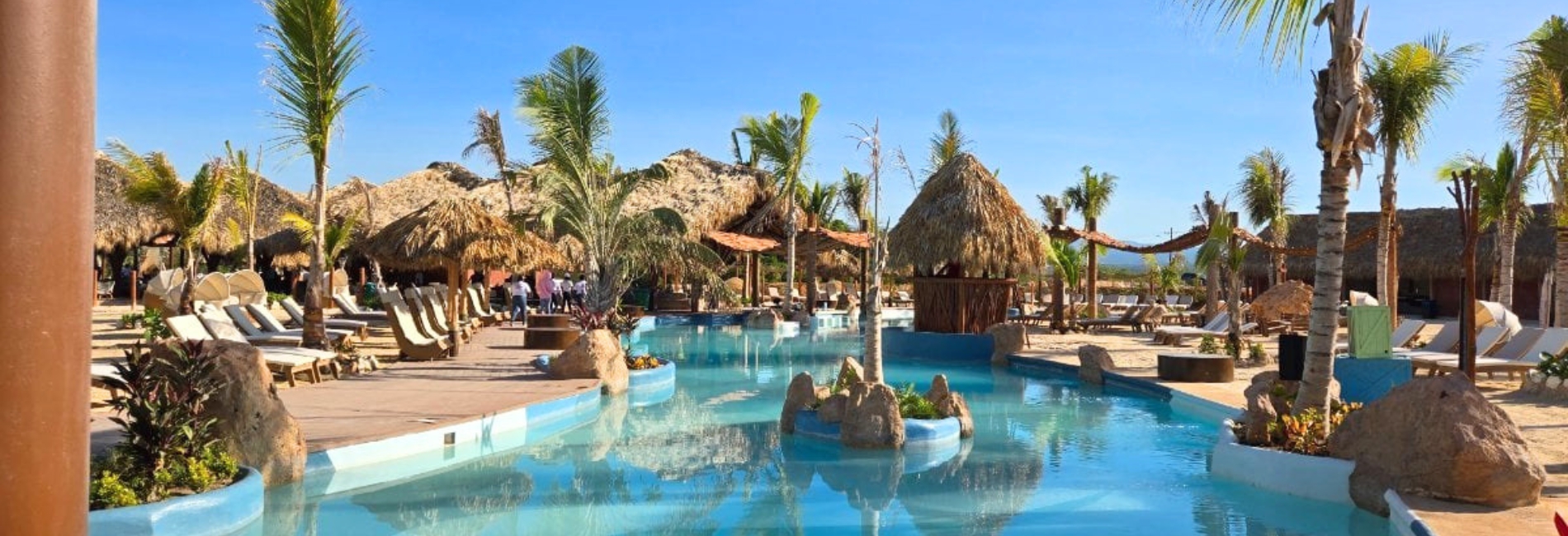 Pool with palapa umbrellas and palm trees at Baby Beach Club, Cabo Rojo