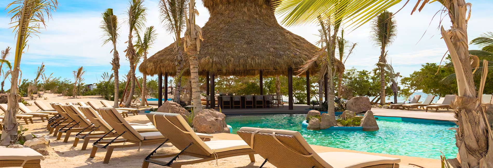 Resort pool area with thatched palapa bar and lounge chairs at Baby Beach Club